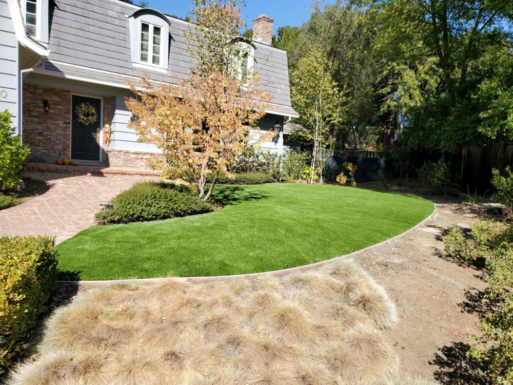 house with trees and a front lawn with artificial turf